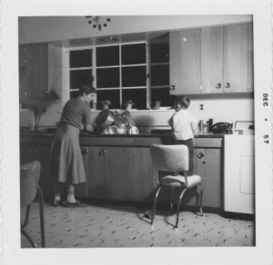 Mum and youngest brother in 1957 kitchen--note clock at top of photo, Dad made that as well!